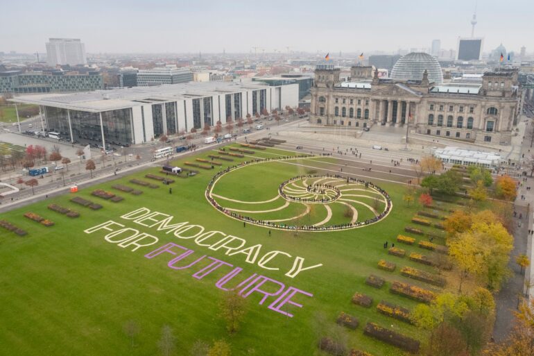 Schriftzug "Democracy for Future" auf der Wiese vor dem Reichstag in Berlin. Foto: Mehr Demokratie e.V.